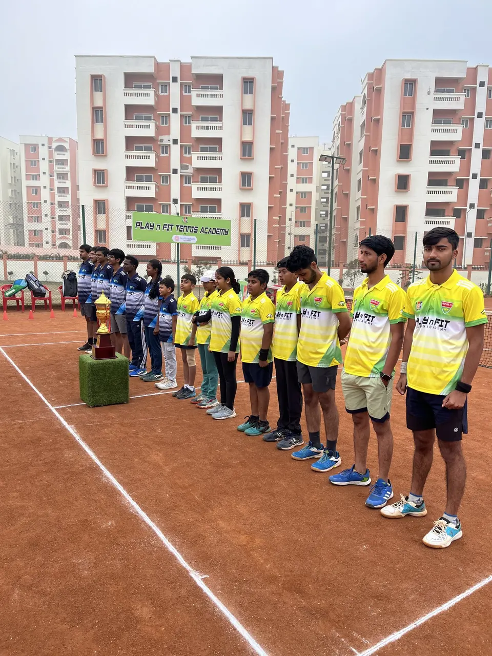 PLAY n FIT squad in yellow and blue kit lined up beside a trophy