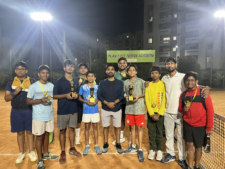 Players holding trophies under the floodlights at PLAY n FIT