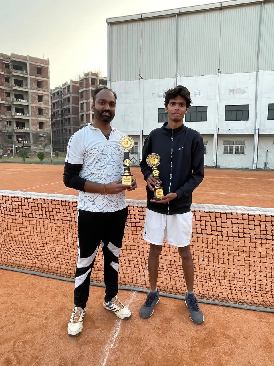 Two players holding trophies on court
