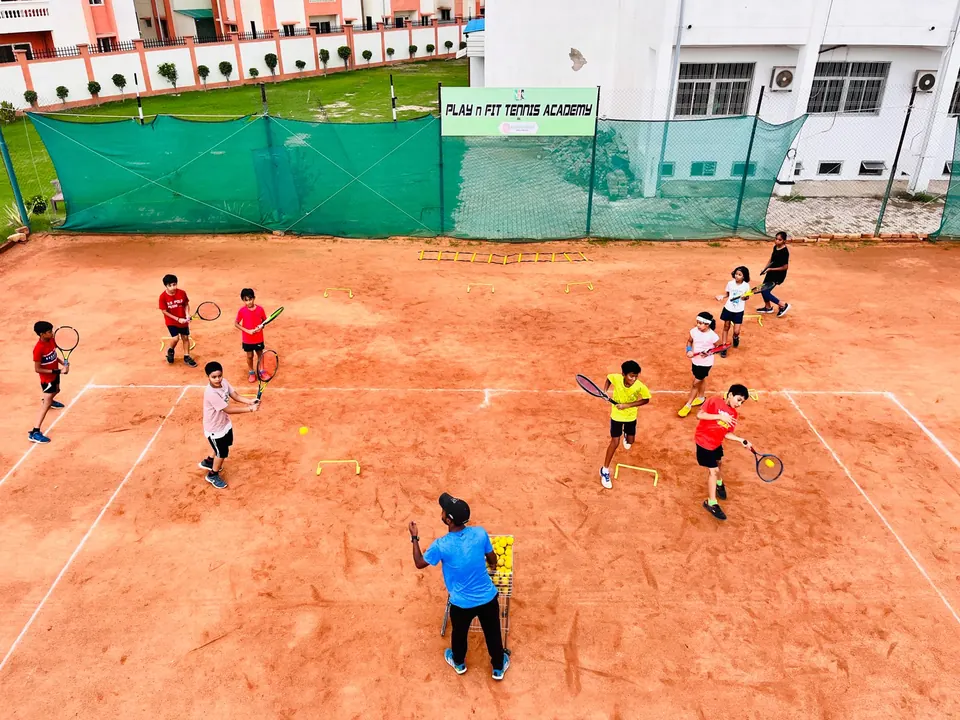 Aerial view of juniors running a footwork drill on a clay court at PLAY n FIT