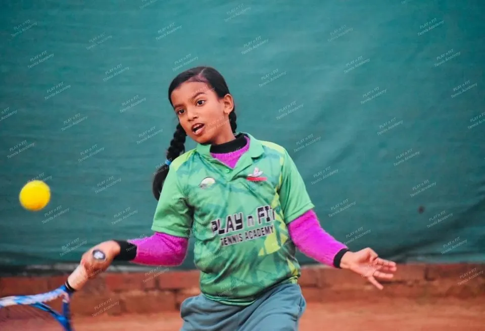 Junior player in green academy kit hitting a forehand