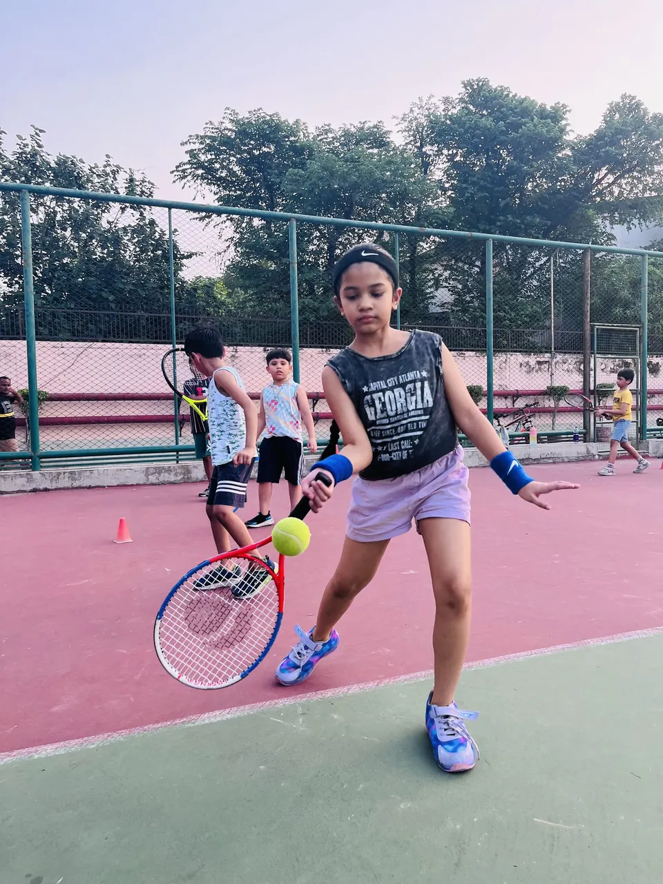 Young player hitting a forehand on a hard court
