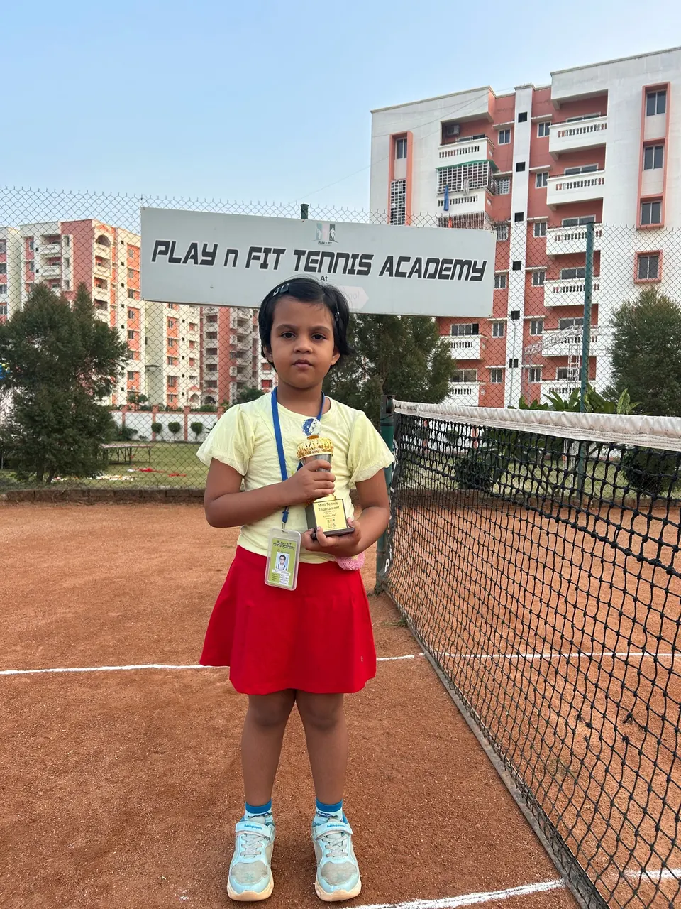 Young player holding a trophy on court